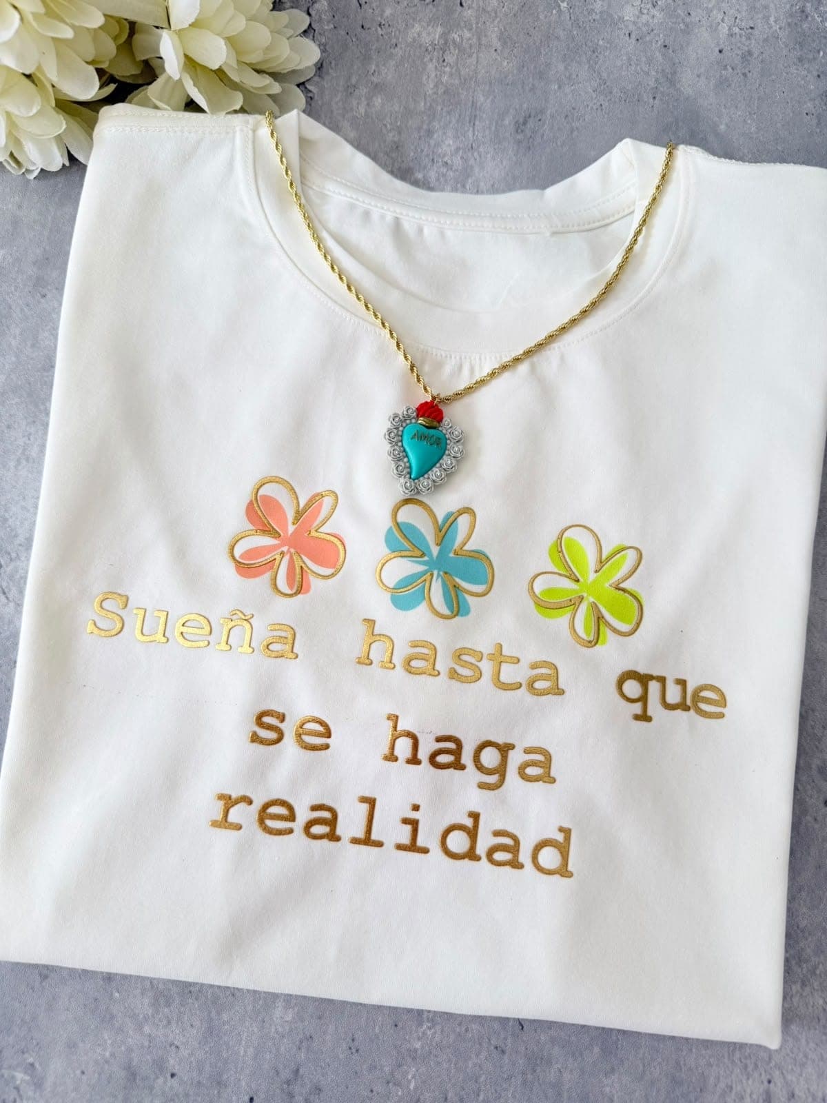 Camiseta blanca con flores y la frase Sueña hasta que se haga realidad