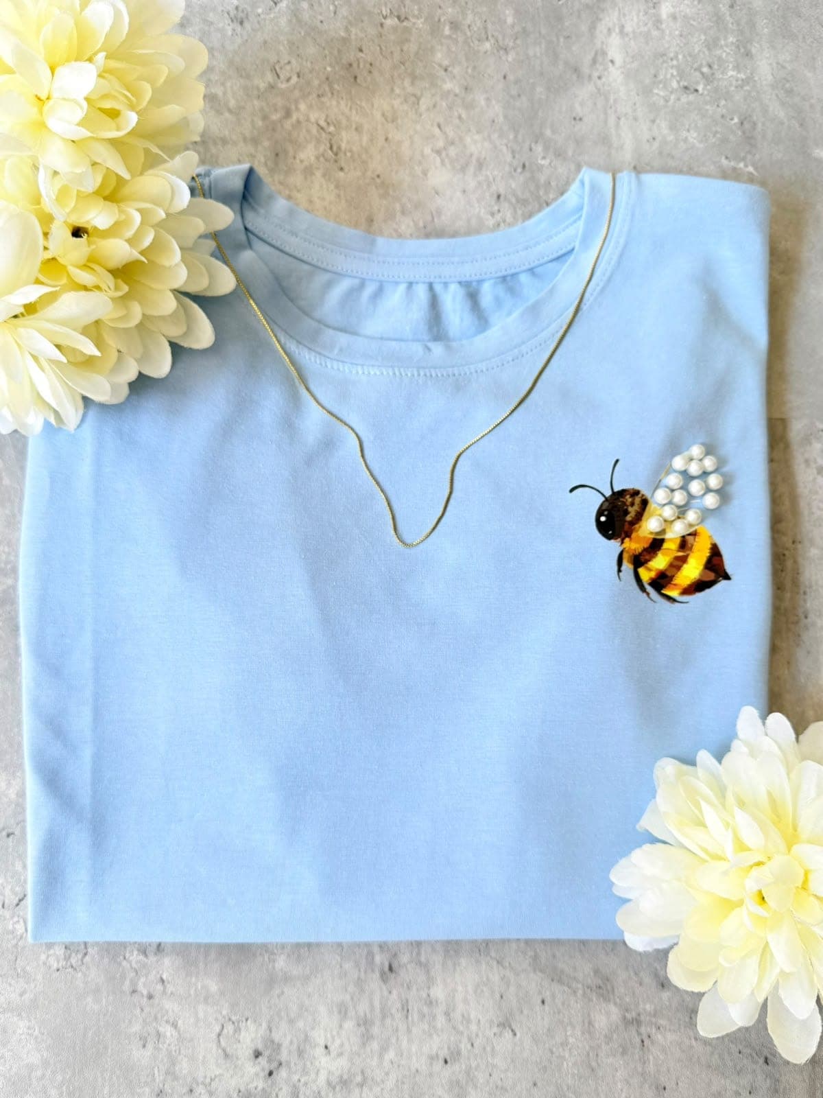 Camiseta azul claro con abeja de perlas en el pecho