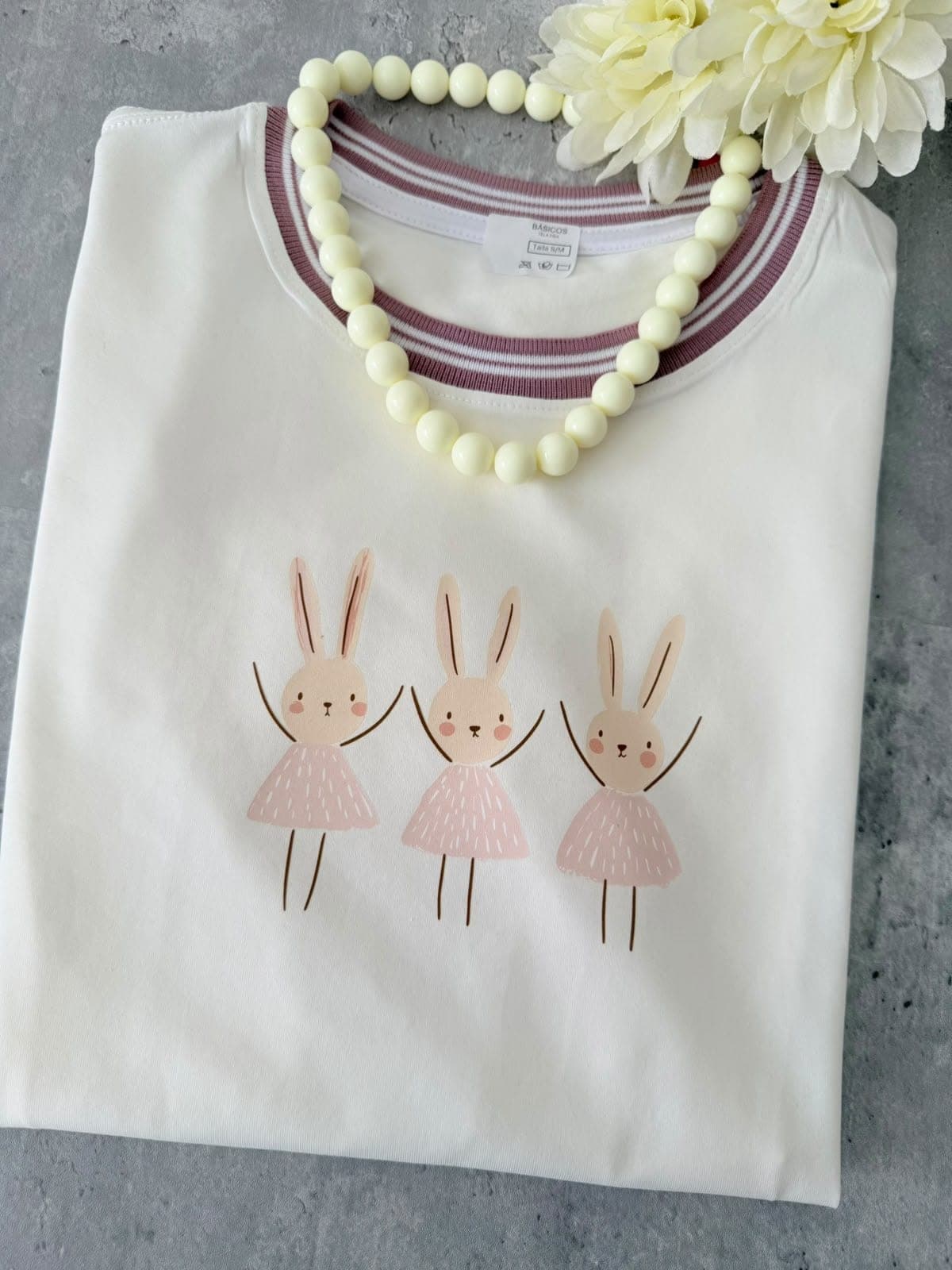 Camiseta crema con tres conejitas bailarinas y cuello a rayas