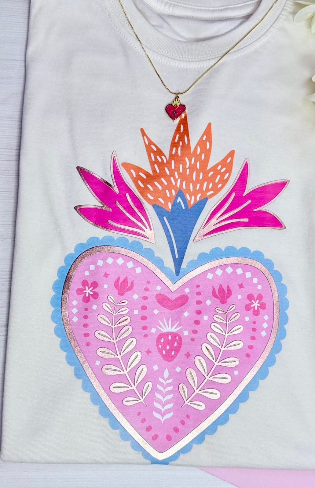 Camiseta blanca con corazón rosado de flores y llama de colores