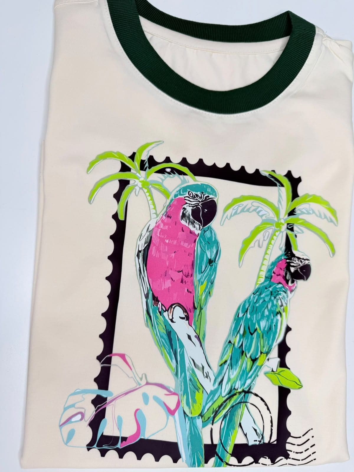 Camiseta crema con cuello verde y dos guacamayas en estampilla