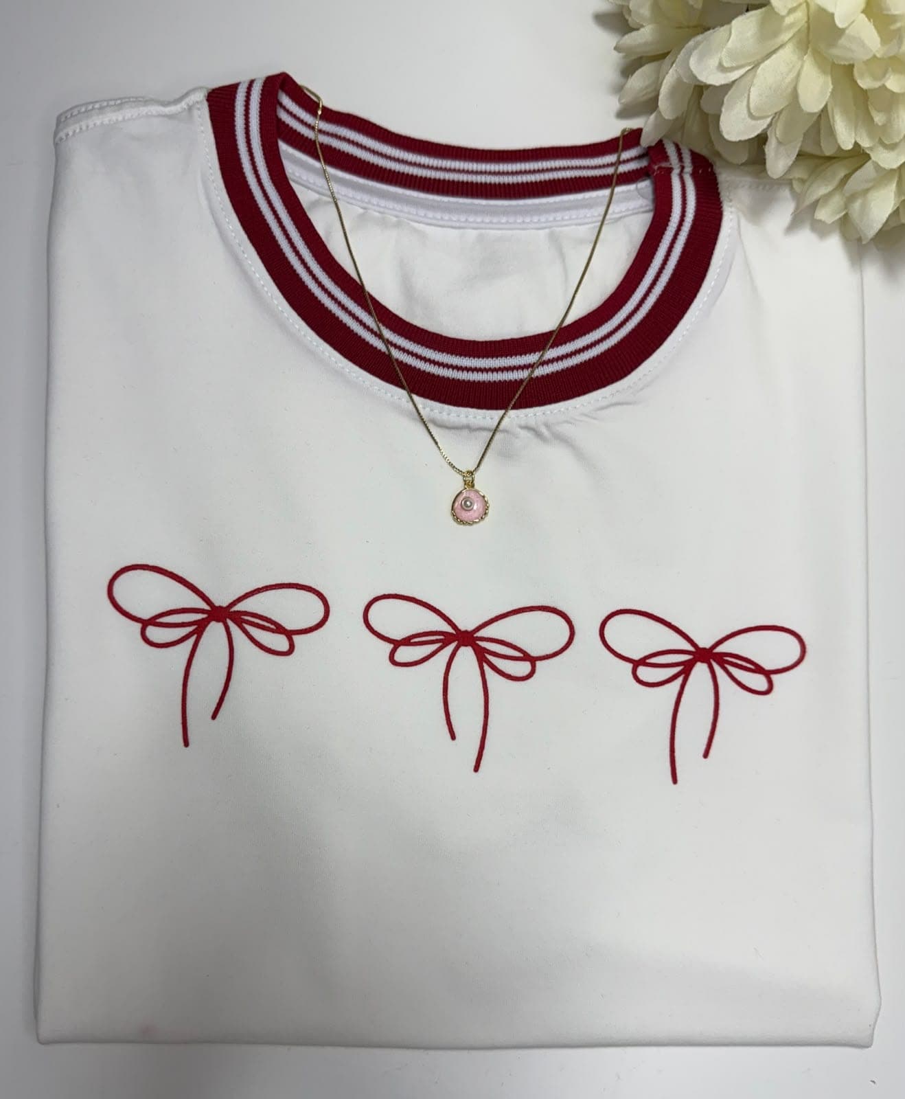Camiseta blanca con tres lazos rojos y cuello a rayas