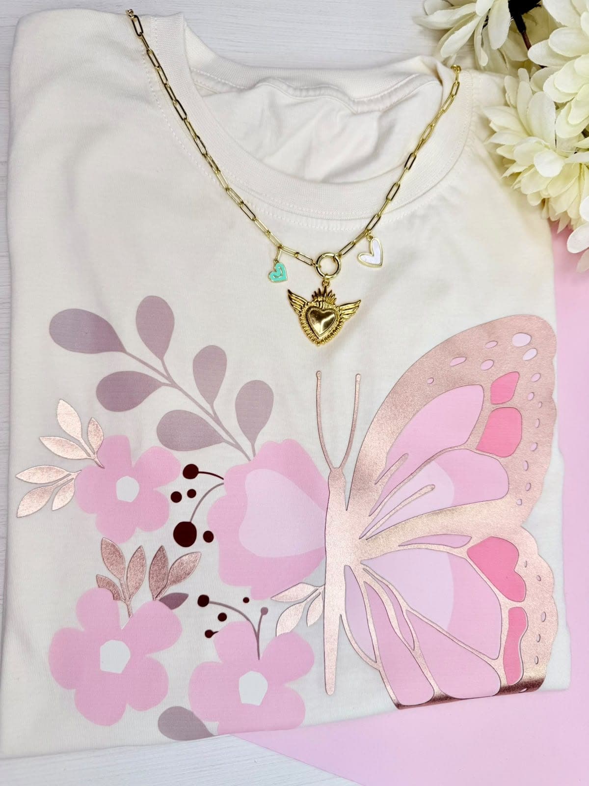Camiseta crema con mariposa rosada y flores