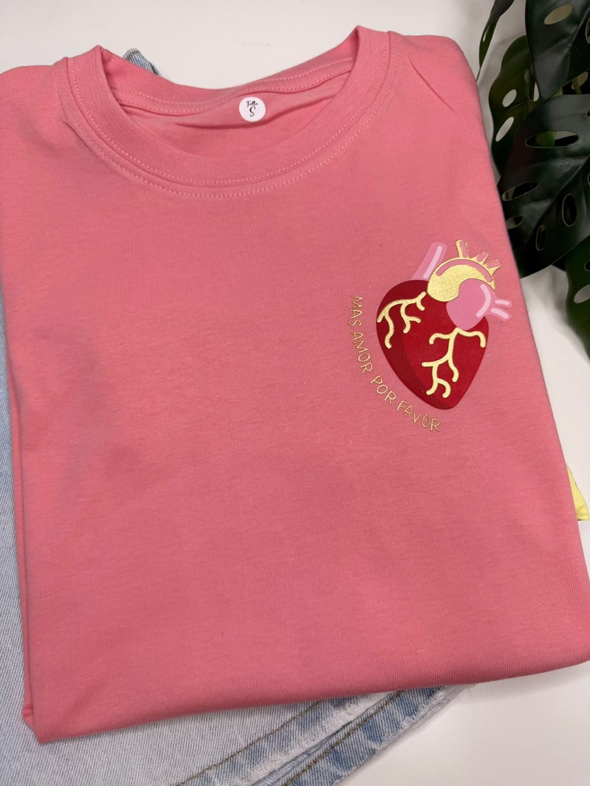 Camiseta coral con corazón pequeño en el pecho y la frase Más amor por favor
