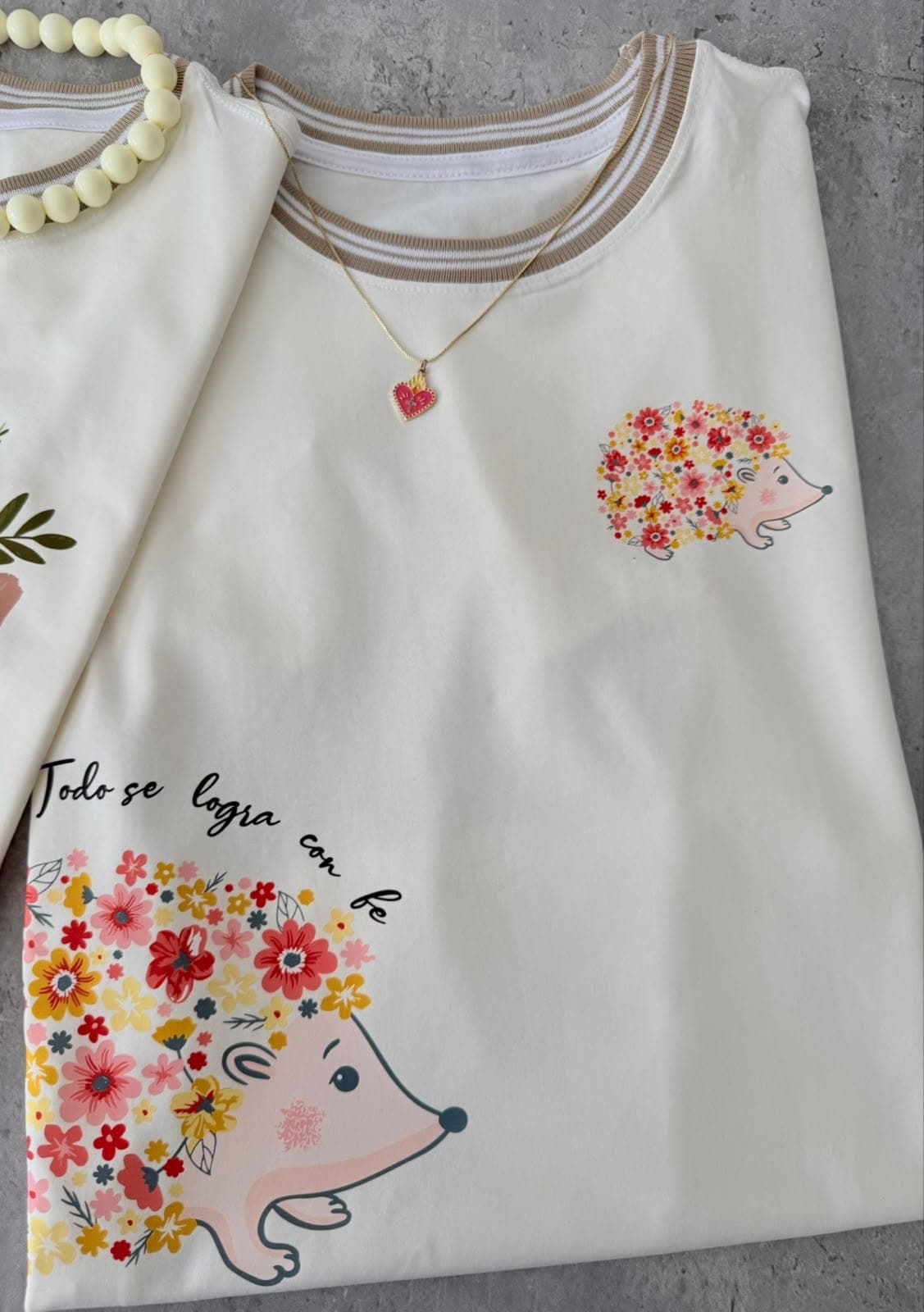 Camiseta crema con erizo de flores y la frase Todo se logra con fe