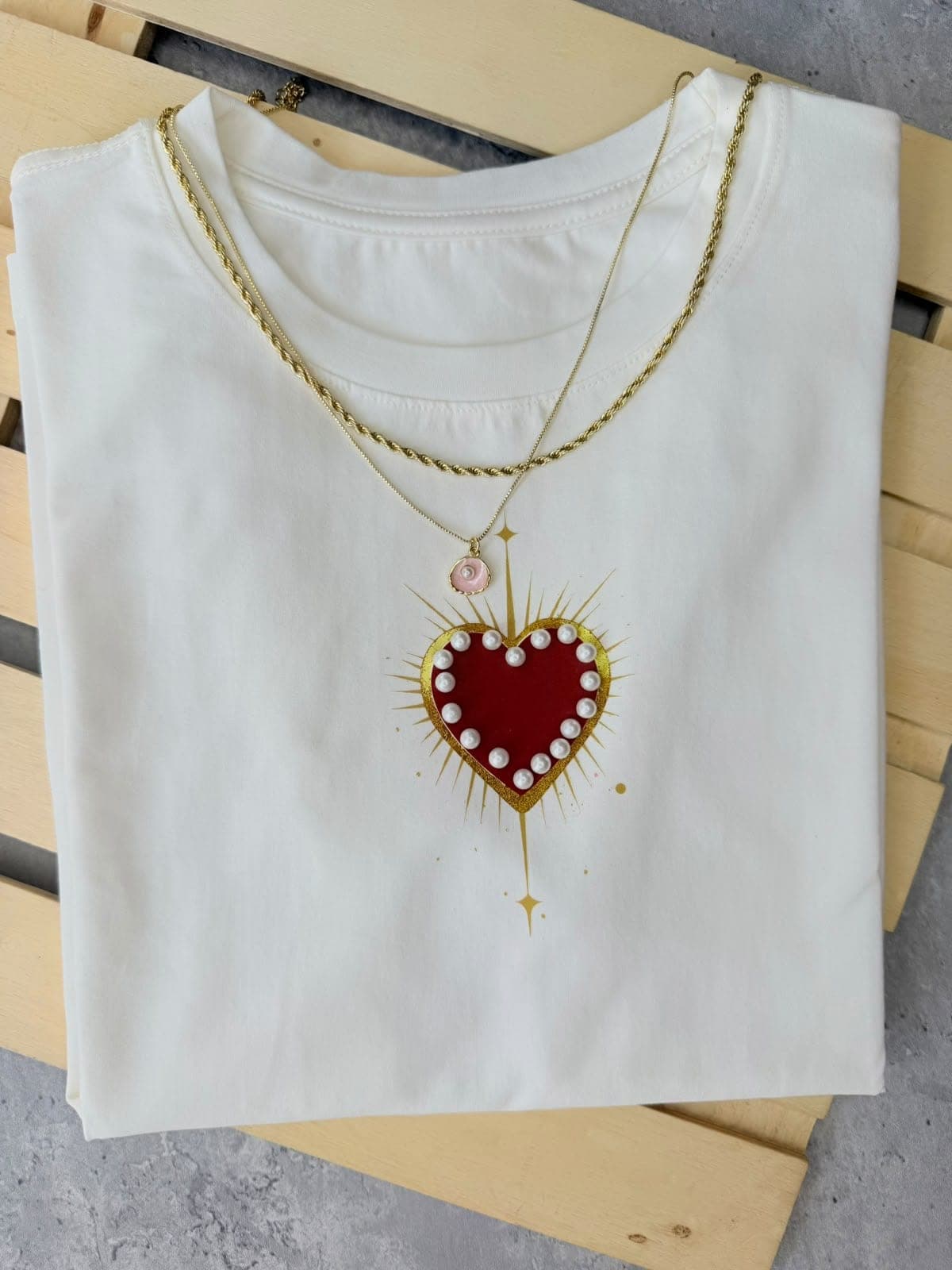 Camiseta blanca con corazón rojo rodeado de perlas