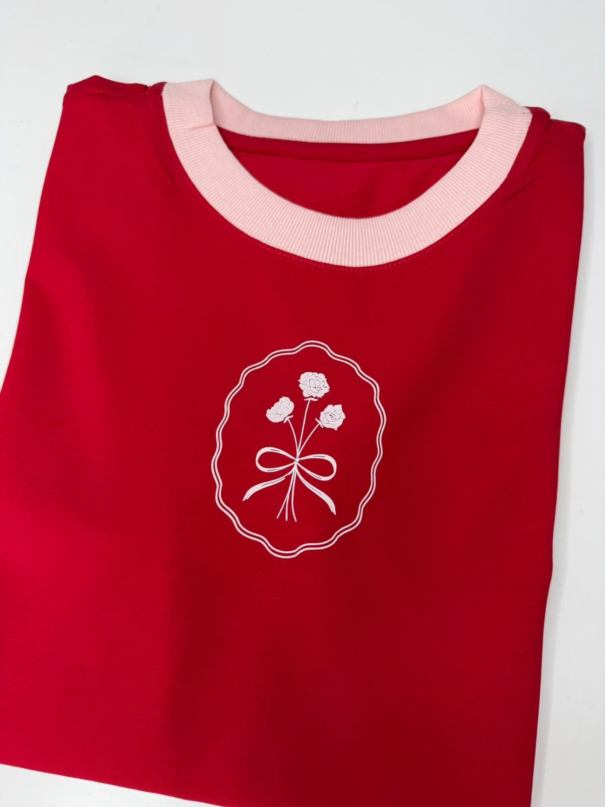 Camiseta roja con cuello rosado y ramo de flores en óvalo