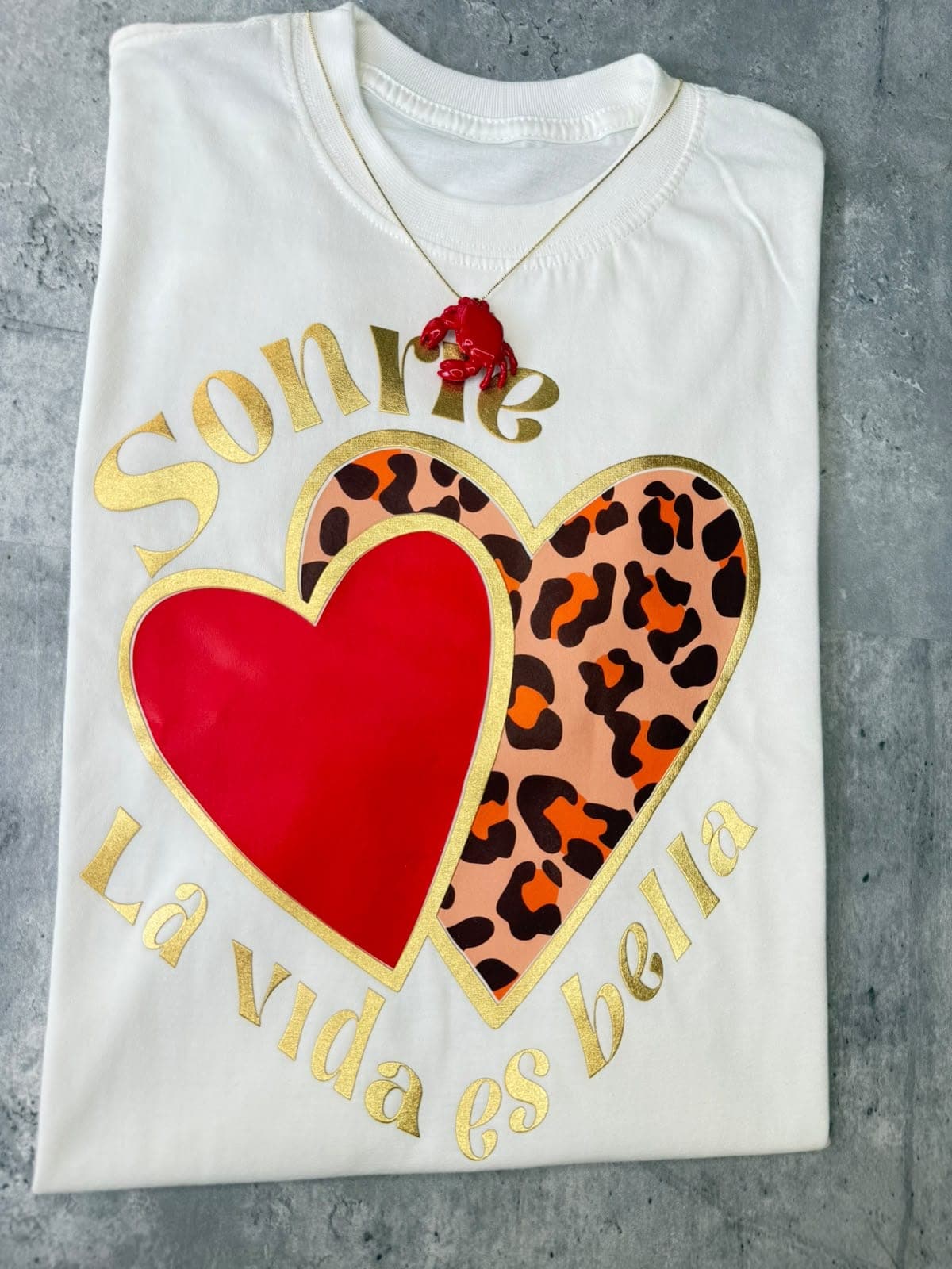 Camiseta blanca con corazones rojo y leopardo y la frase Sonríe la vida es bella en dorado