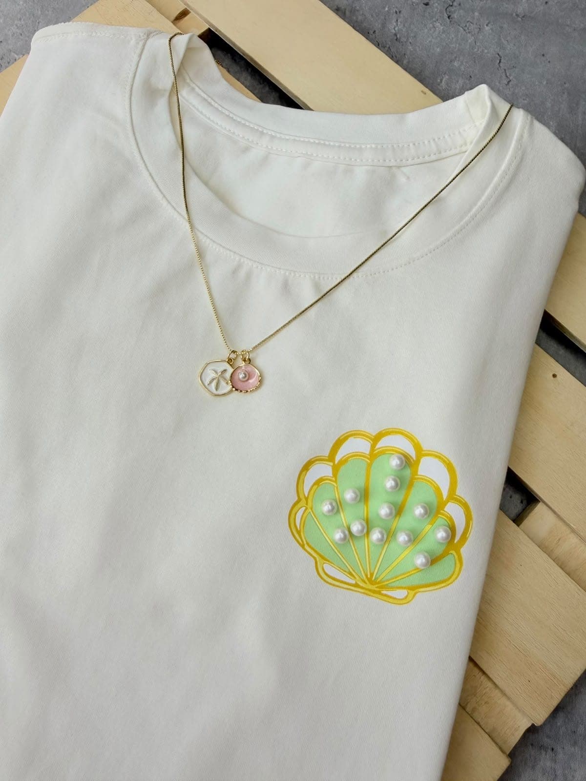 Camiseta crema con concha verde y perlas