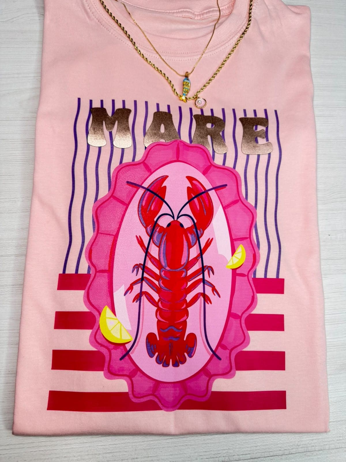 Camiseta rosada con langosta en marco y la palabra Mare