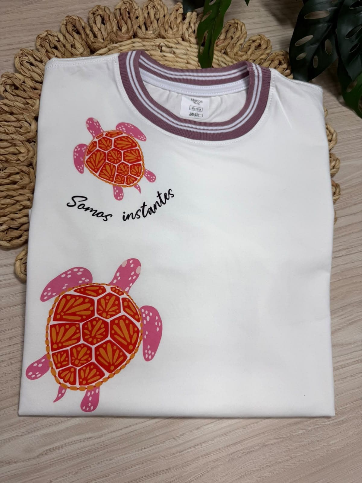 Camiseta blanca con dos tortugas y la frase Somos instantes, cuello en contraste