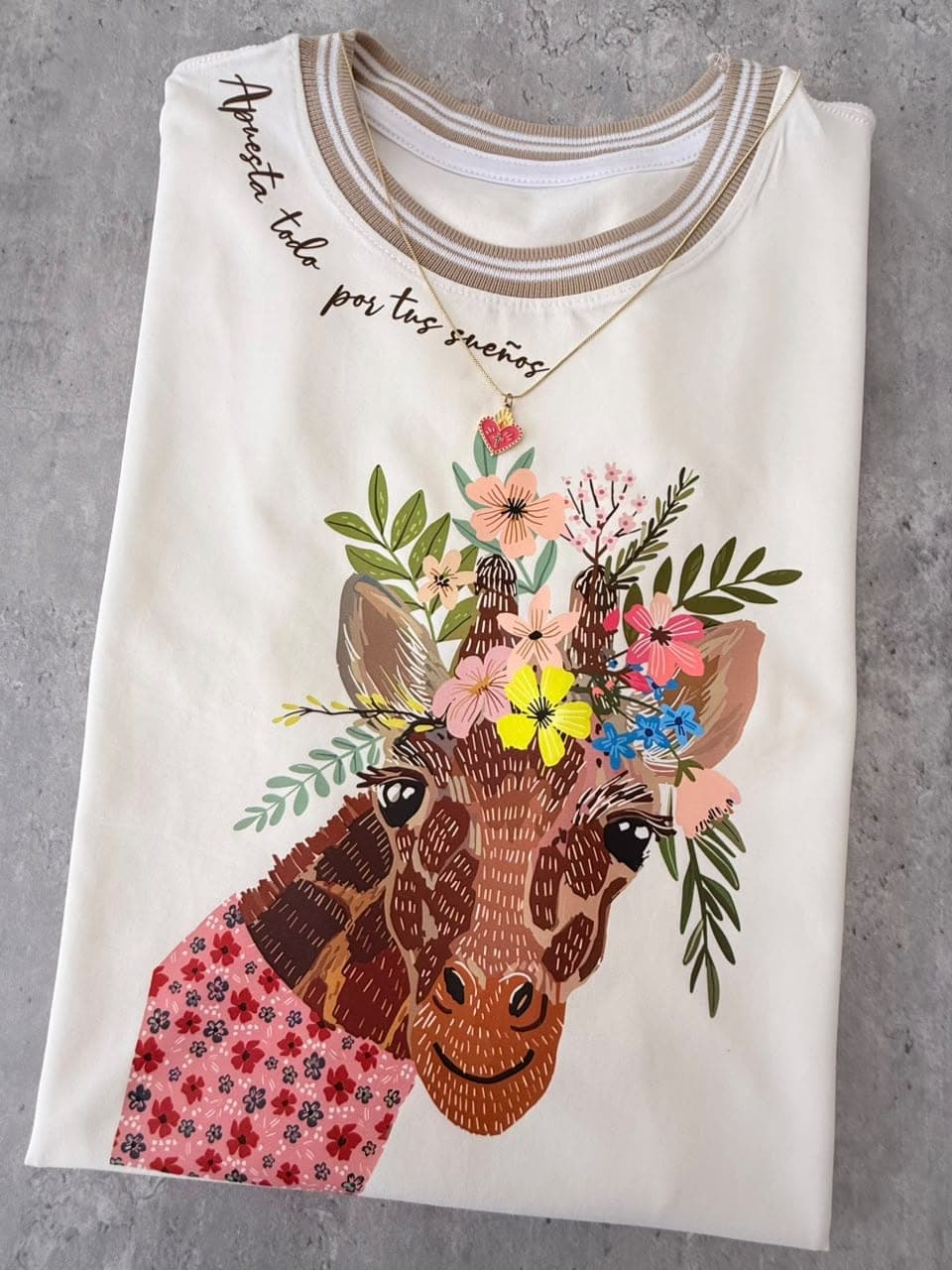 Camiseta crema en tela fría con jirafa con corona de flores y la frase Apuesta todo por tus sueños