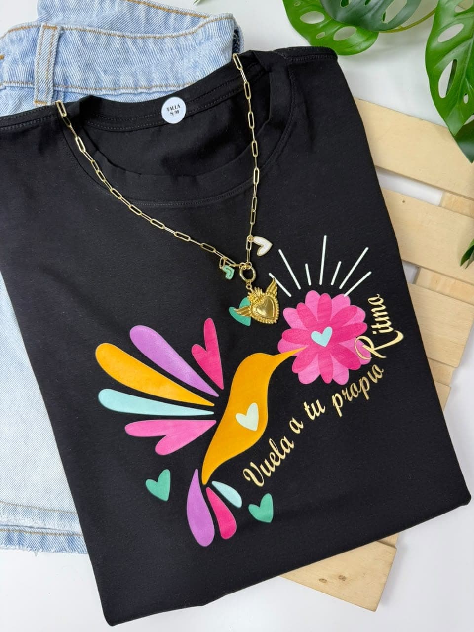 Camiseta negra en tela fría con colibrí de colores y la frase Vuela a tu propio ritmo