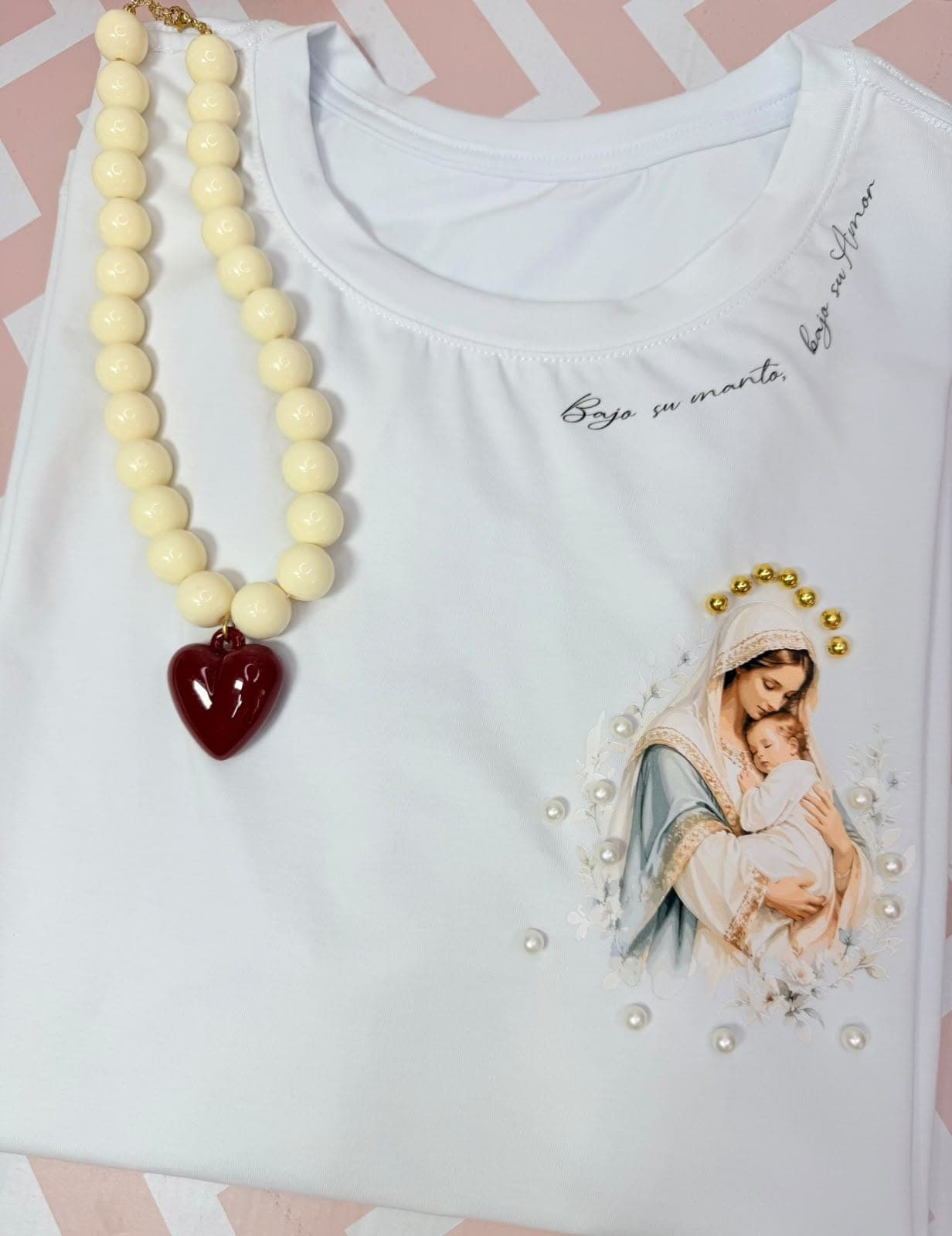 Camiseta blanca con la Virgen y el niño y la frase bajo su amor