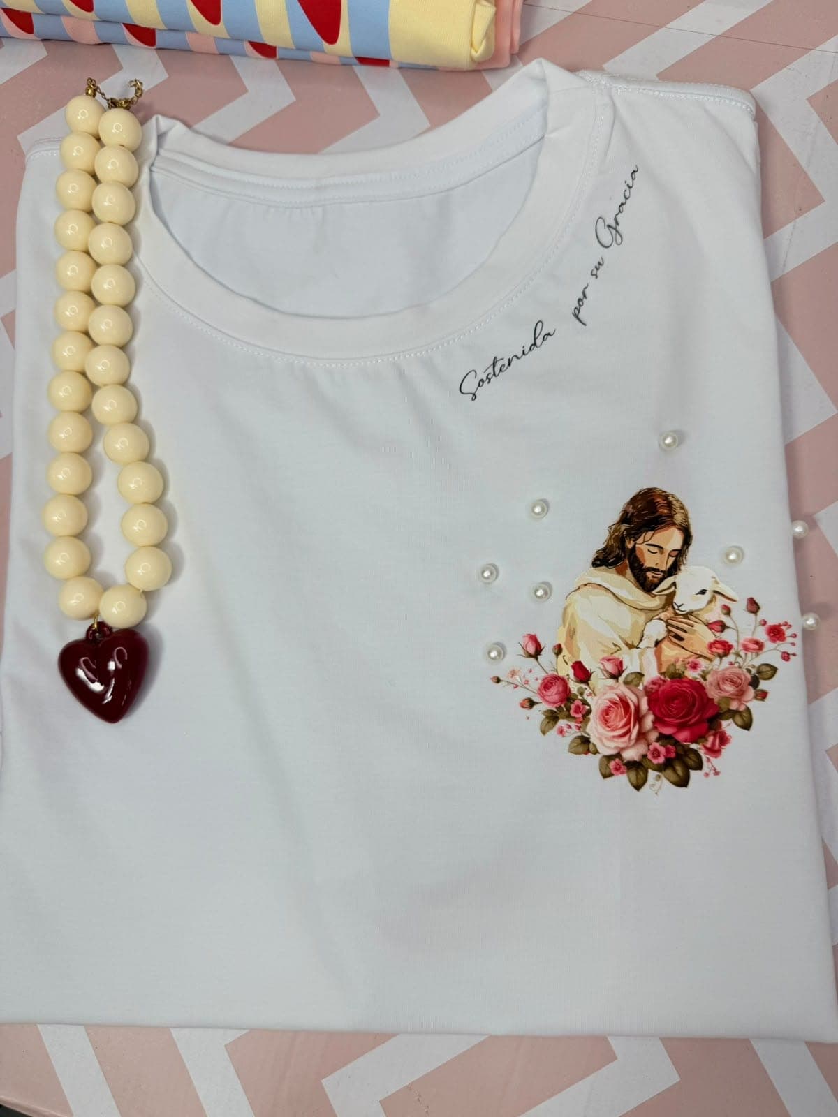 Camiseta blanca con Jesús entre rosas y la frase por su gracia
